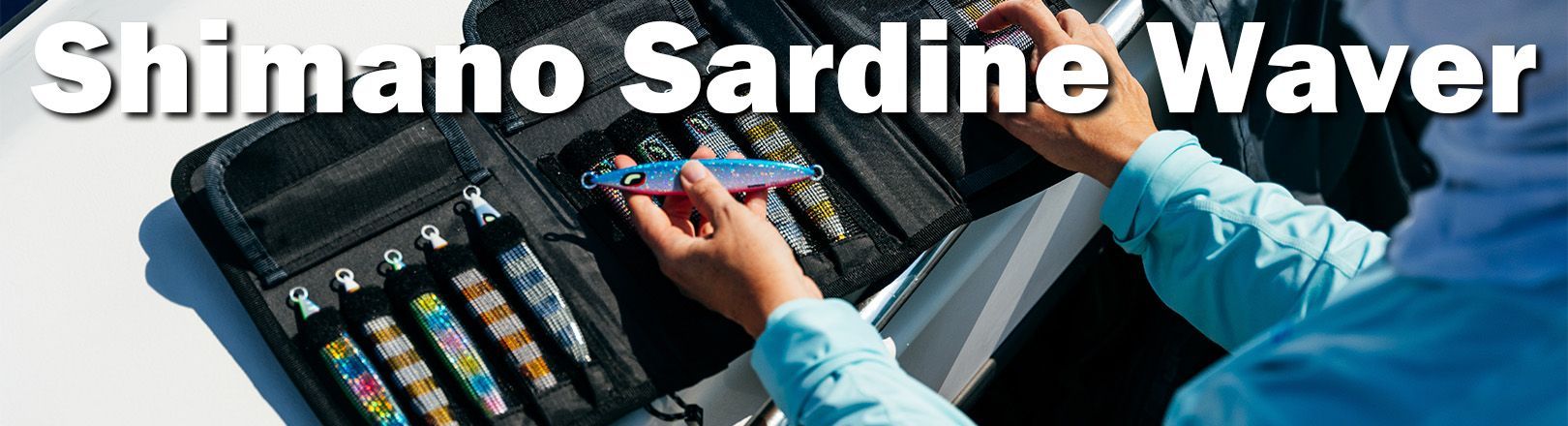 Person holding a colorful fishing lure above an open case containing several fishing lures on a boat.
