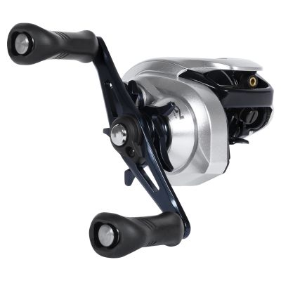 Shimano Tranx 200AXG Baitcasting Reel, shown from 3/4 handle side. Features silver-colored body with dark blue handle arm and star drag, black paddle grips, and visible &ldquo;Hagane&rdquo; logo on gear housing.