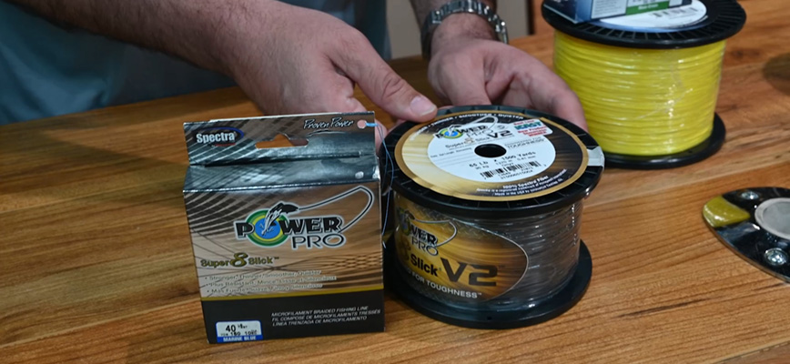 Person displaying PowerPro Super 8 Slick and PowerPro Slick V2 braided line spools.