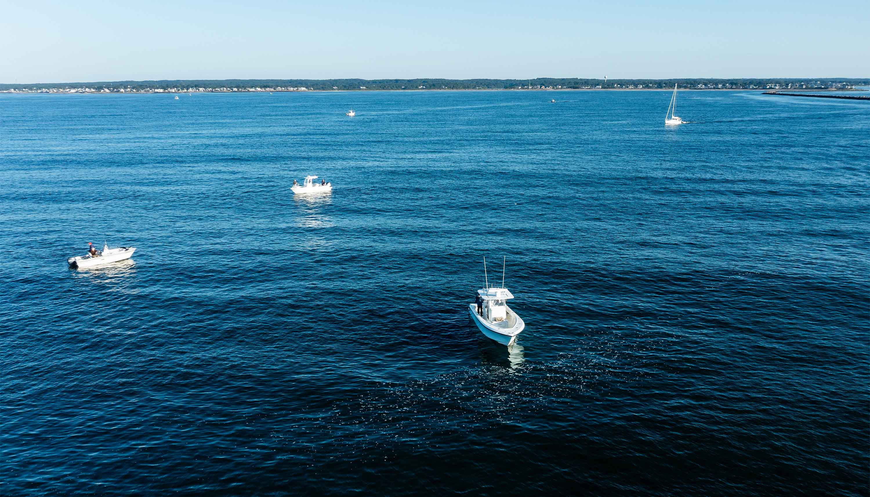 Chasing False Albacore image showing several fishing boats on the ocean near a distant coastline.
