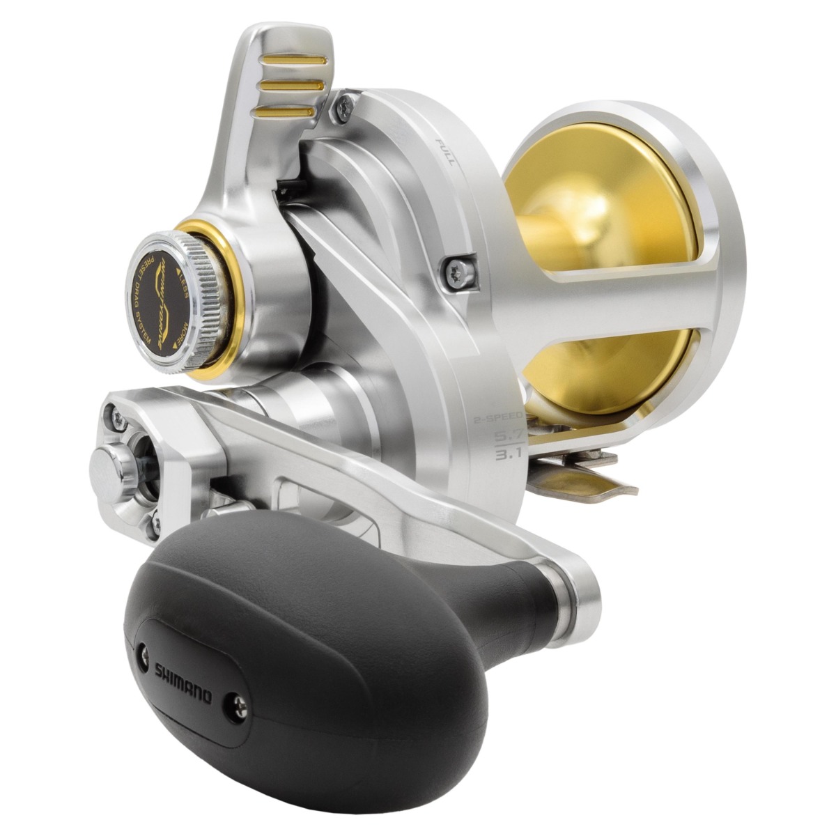 Silver and gold-colored Shimano reel with large black handle grip, visible drag lever and spool. Marked with gear ratios “5.7:1 / 3.1:1” and “2-SPEED.” Text “SHIMANO” engraved on the handle cap.