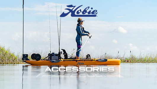 Hobie Accessories. Shop Now. Background shows a woman fishing on an orange Hobie kayak, decked out with Hobie accessories.