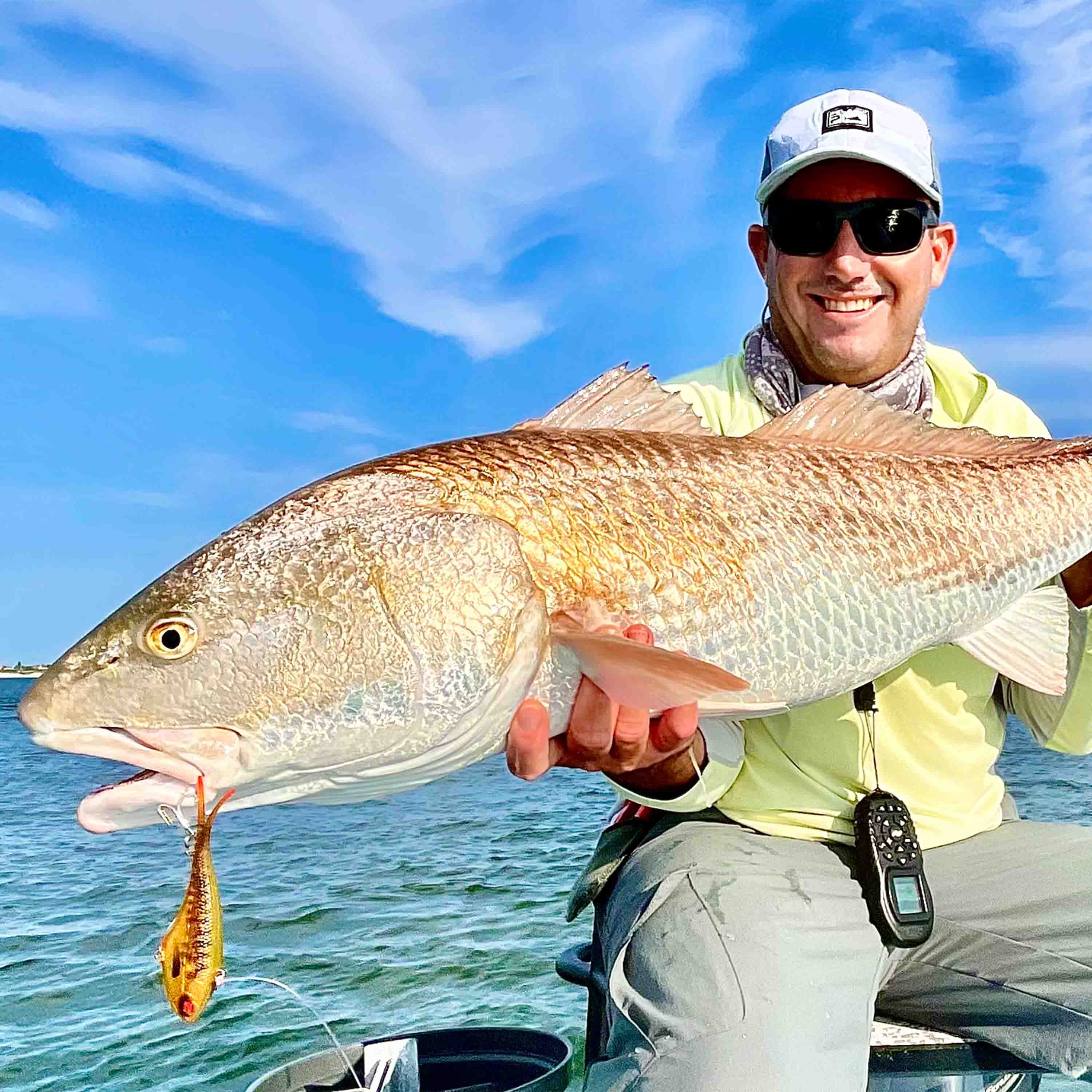 Jarad Dingo Boshammer holds a large redfish while fishing from a boat on open water.