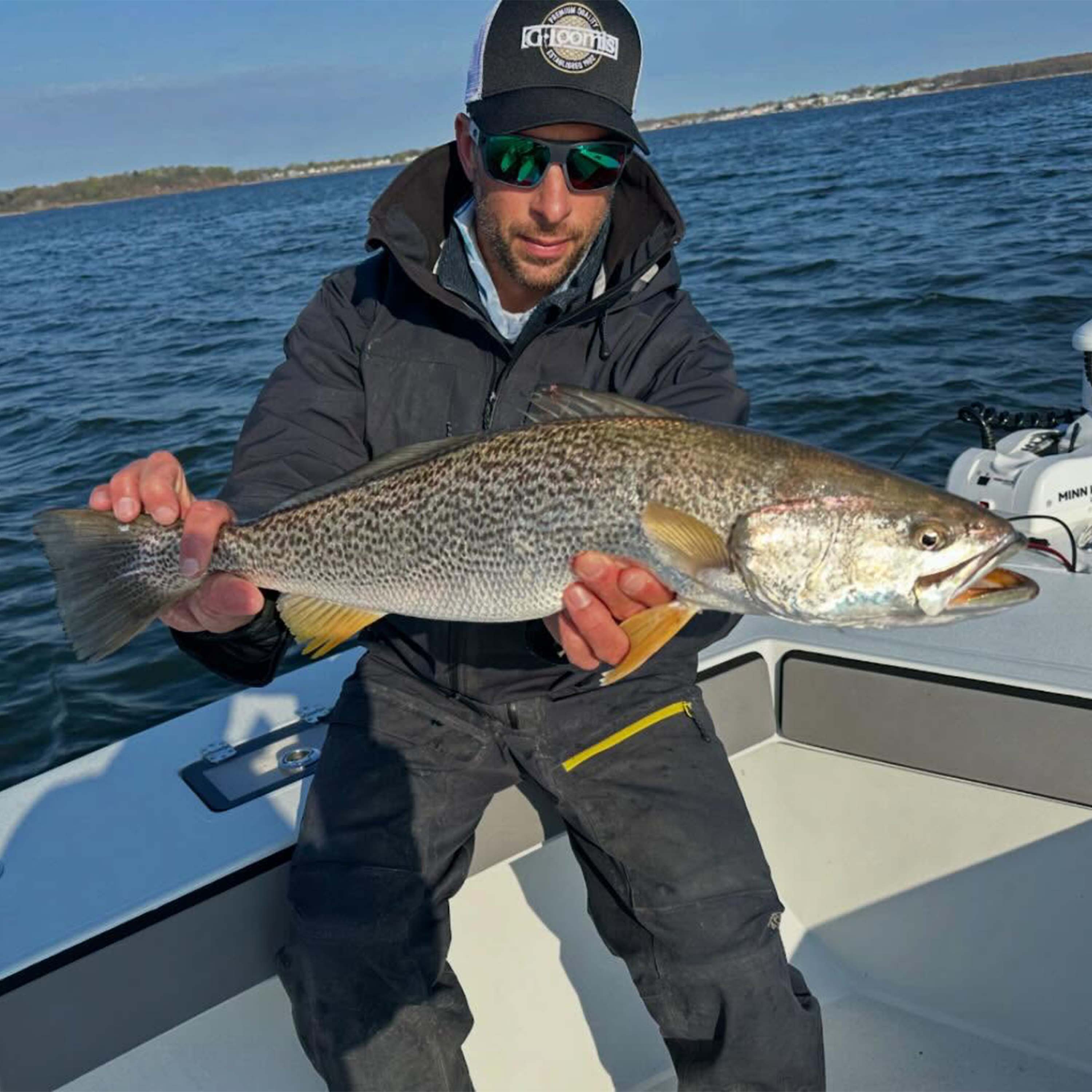 Captain Mike Roy holding a large spotted sea trout on a fishing boat in Connecticut coastal waters.